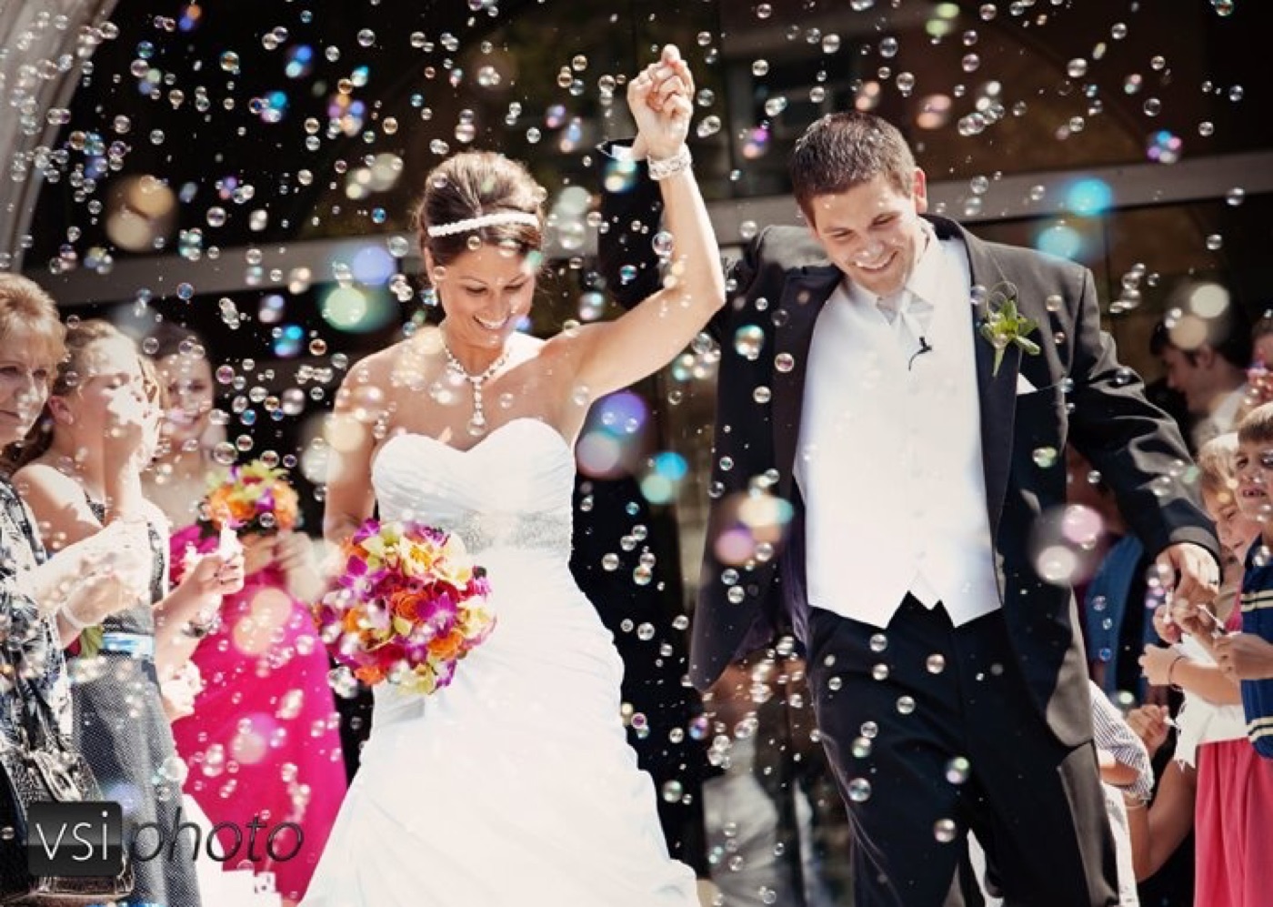 A bride and groom dancing through a cloud of bubbles
